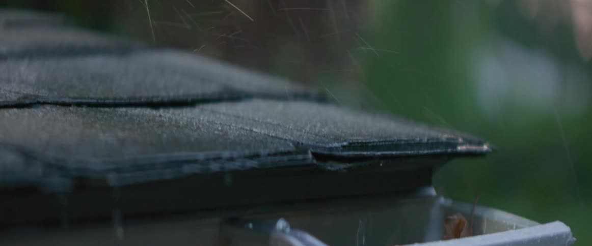 Rain falling on rooftop and dripping into gutters