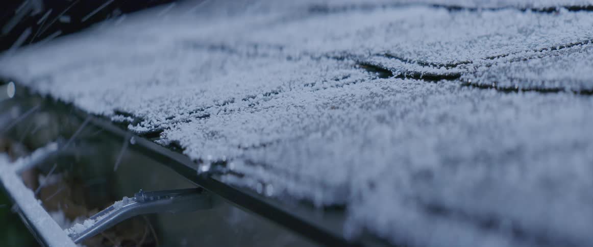 Snow falls on a rooftop and gutter on a chilly winter day