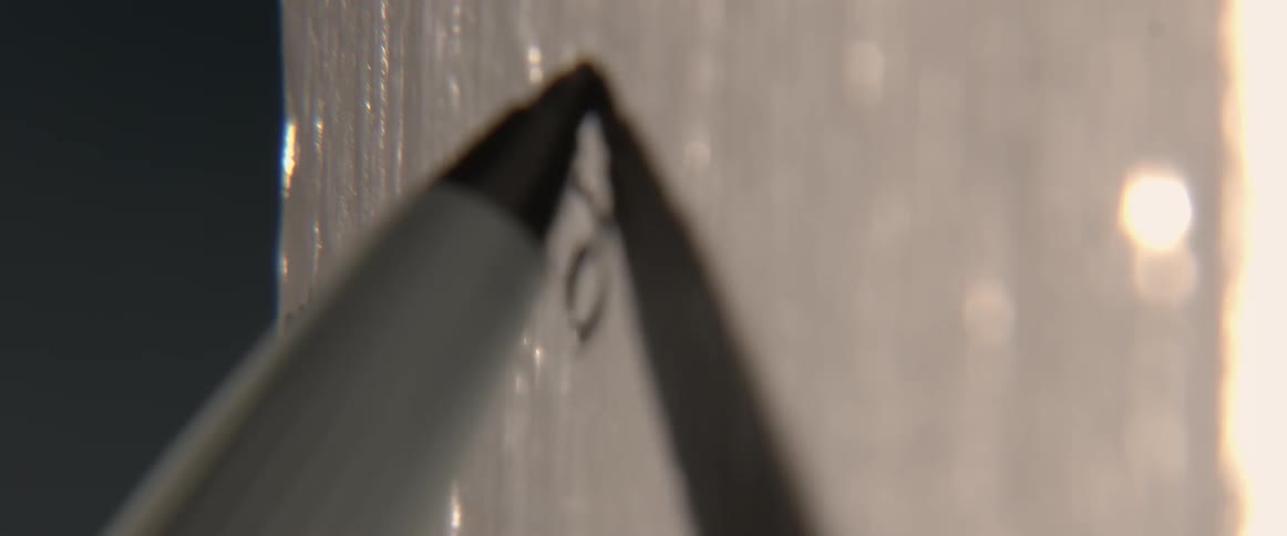A pen sketches on a glass surface with words written on it