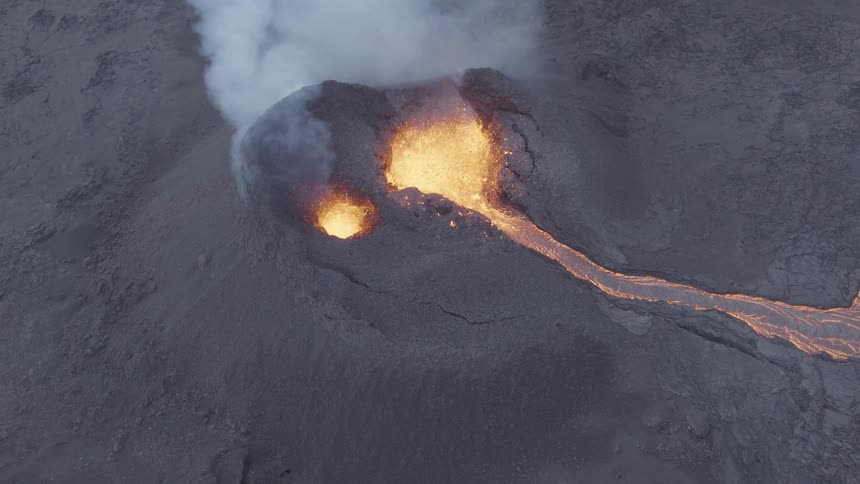 Erupting volcano crater spewing glowing lava and smoke over a dark barren terrain