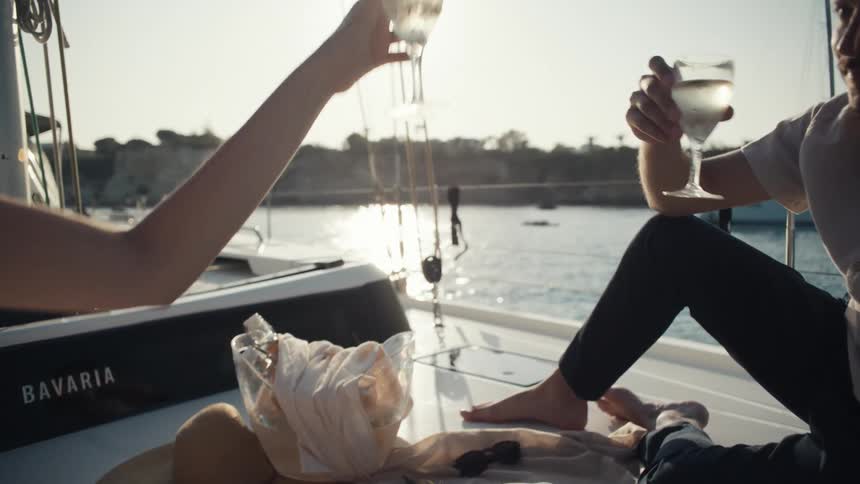 Couple toasting champagne while sitting on a yacht in the late afternoon