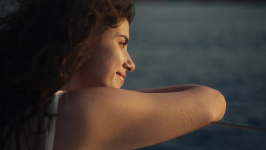 Curlyhaired woman smiling while resting her arms on an outdoor surface
