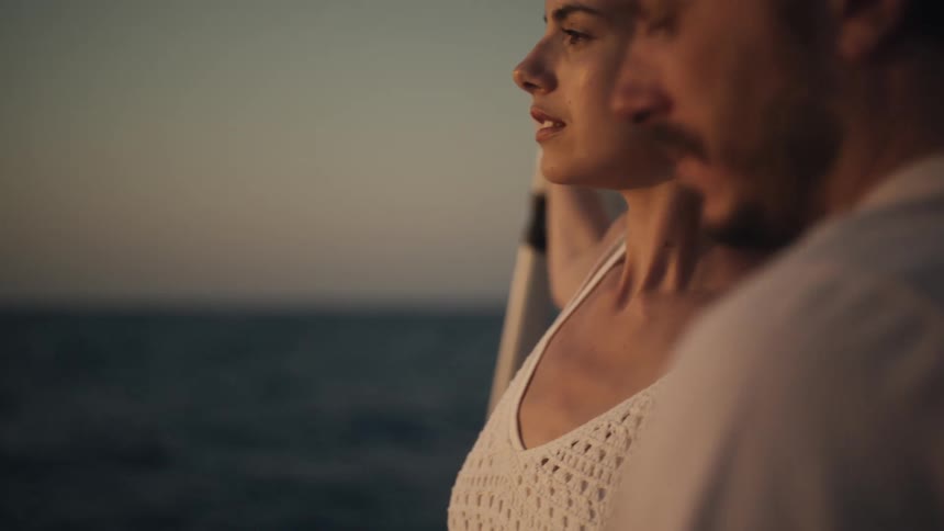 Woman and man looking at the sea during sunset