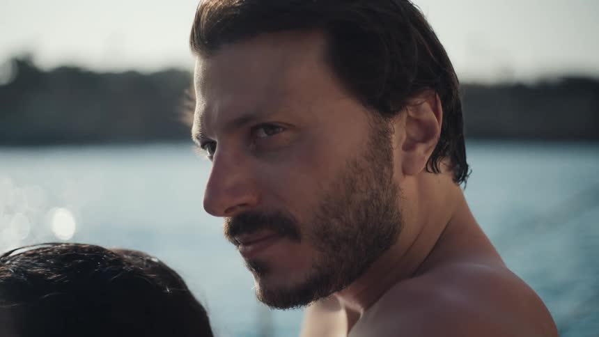 Wet haired man hugging a woman by the sea