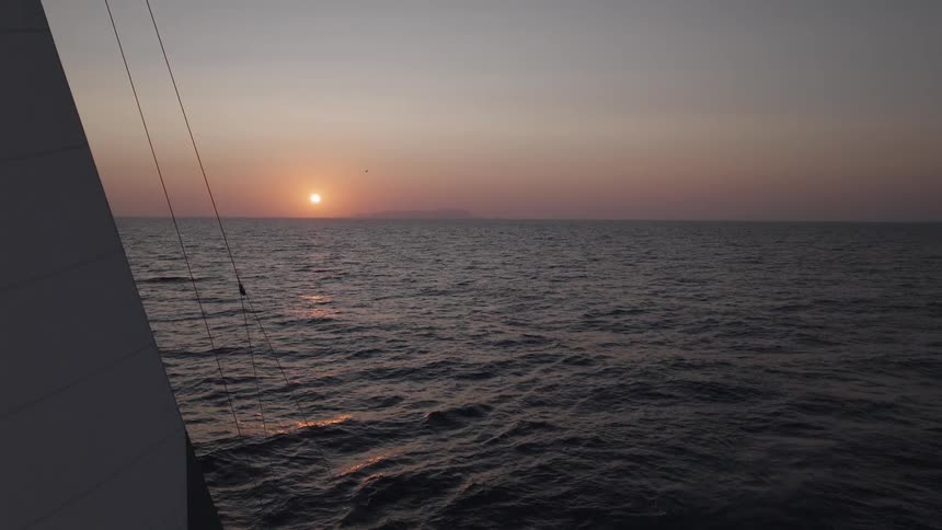 Landscape of a sailing boat on the ocean with the sunset on the horizon