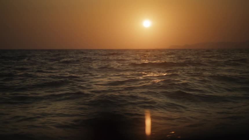 Gentle ripples in the ocean with the sunset on the horizon