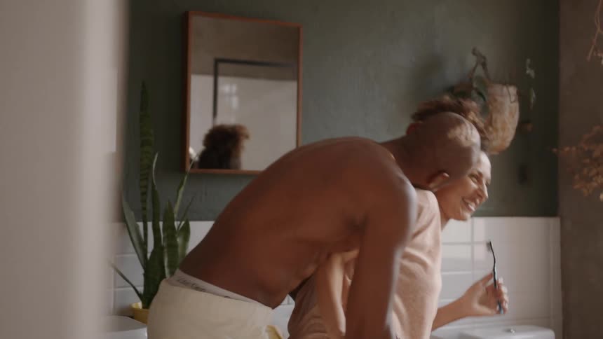 Man lovingly hugging his wife in the bathroom