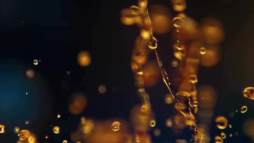 A dark scene with a glow and some sparks and liquid bouncing up