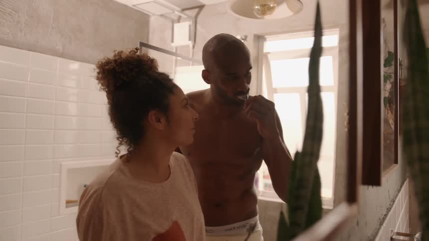 A couple brush together in the bathroom