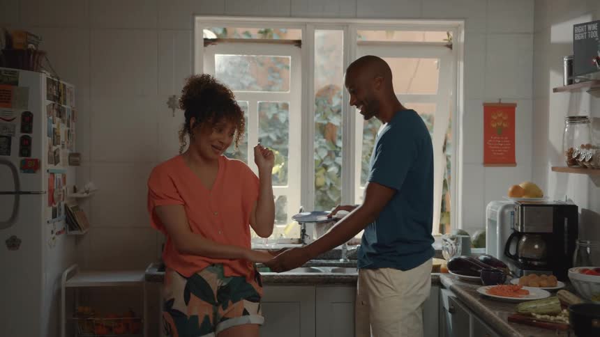 A playful couple in their kitchen interacting and laughing together while preparing a meal