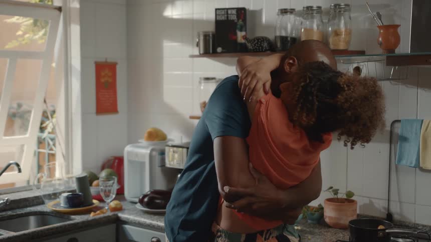 A couple kiss in the kitchen