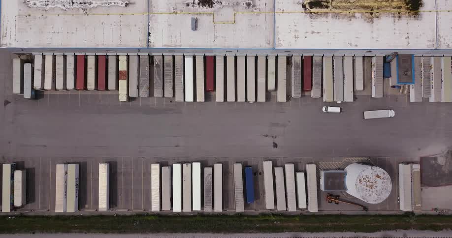 Trucks and containers line up behind buildings