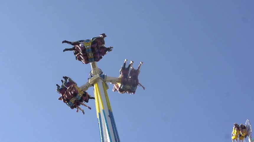 An amusement ride that is swinging people around on a sunny day
