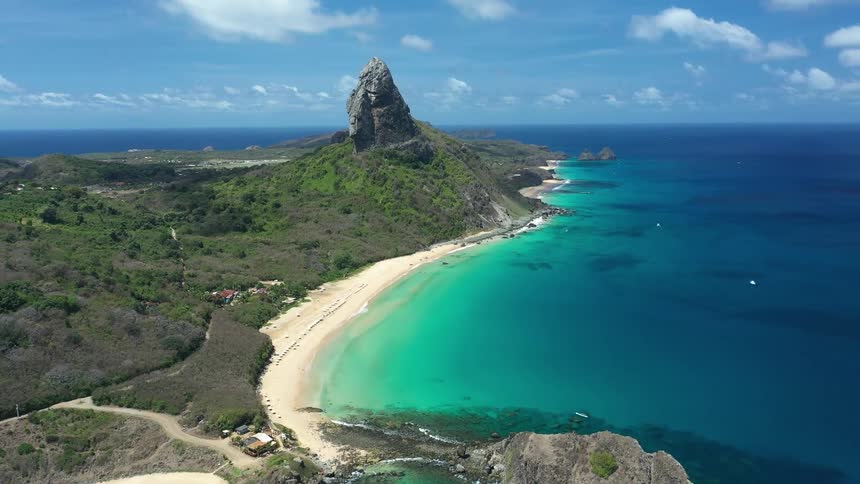 Light sandy beach with turquoise sea and morro do pico in the background in fernando de noronha
