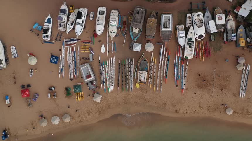Aerial view of boats and kayaks lined up on the sand near the sea