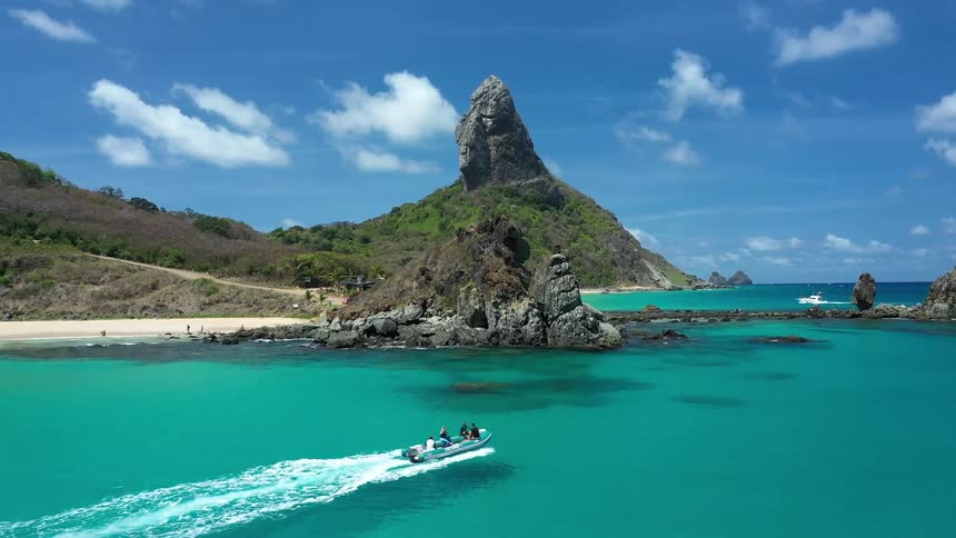 People in a small boat traveling around an island with turquoise blue waters