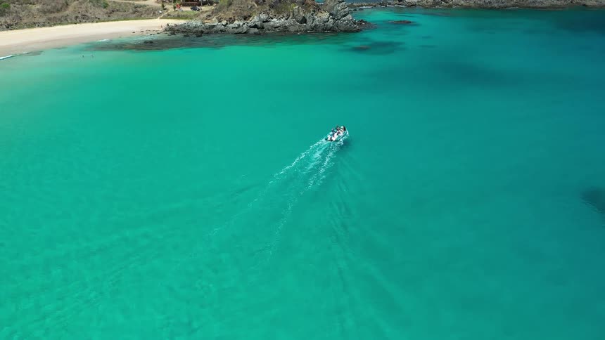 Boat sailing in turquoise sea near rocky formations