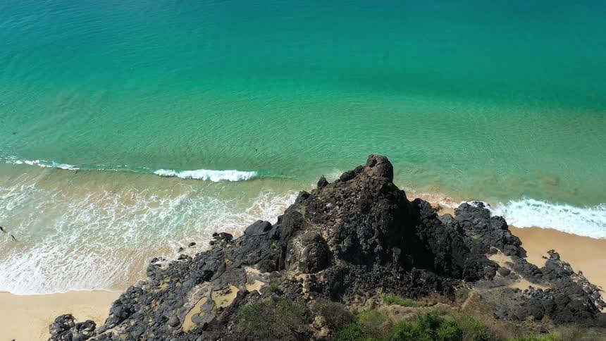 Golden sand beach with turquoise sea viewed from a rocky cliff