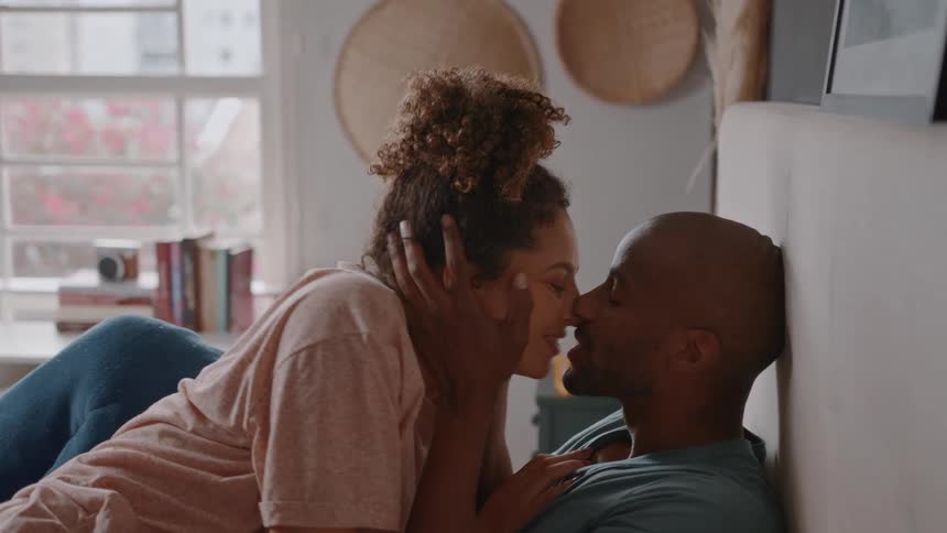 Woman and a man caressing each others faces in bed