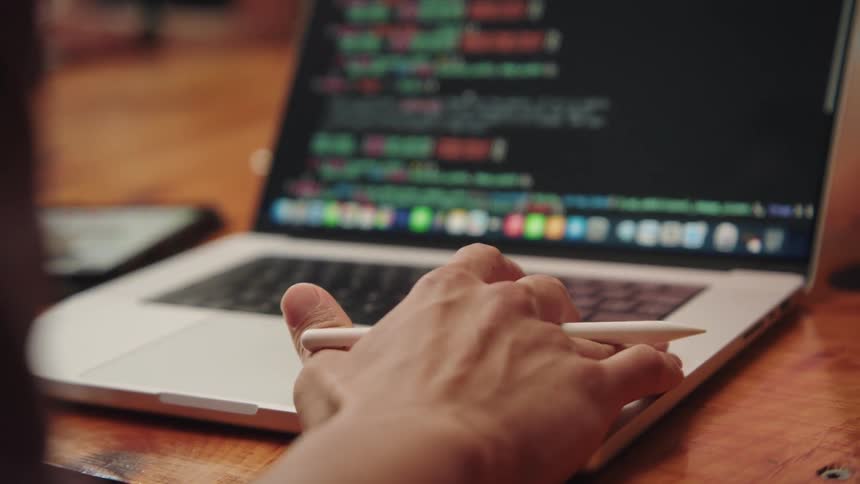 Hand holding a digital pen and interacting with a laptop on a table