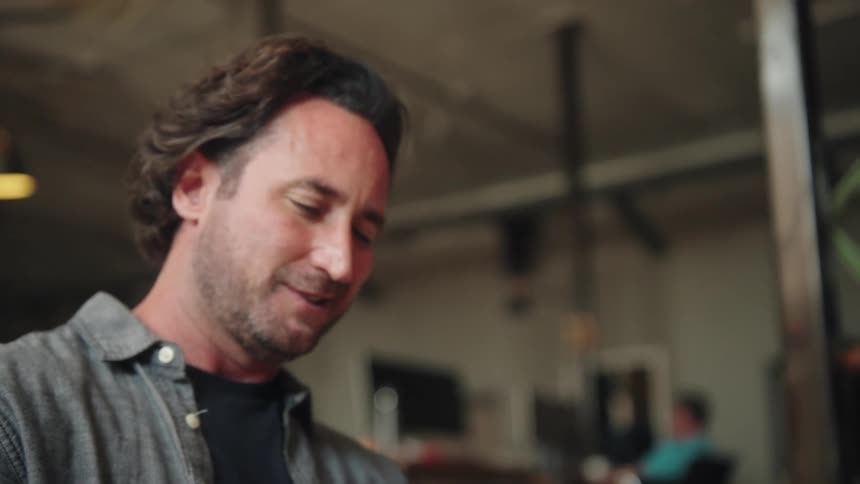 A shot of a mans hands as he scrolls through content on a tablet he looks up and smiles at the end of the video