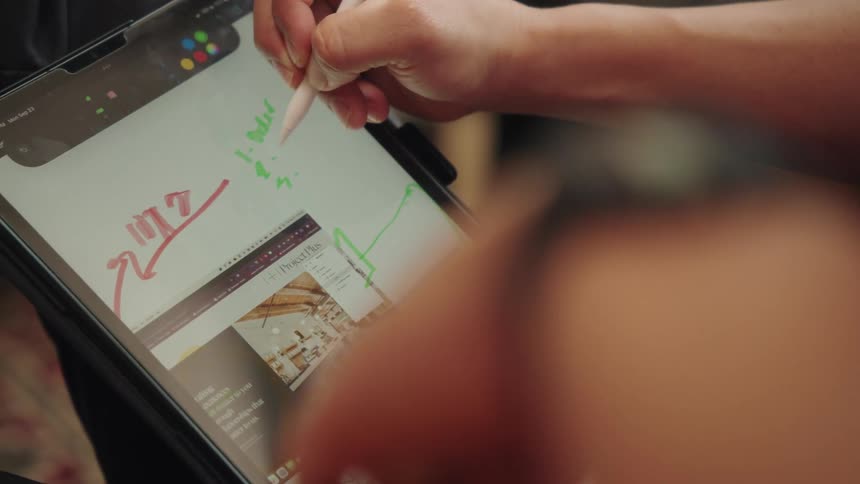 Hand with a pen writing on a tablet