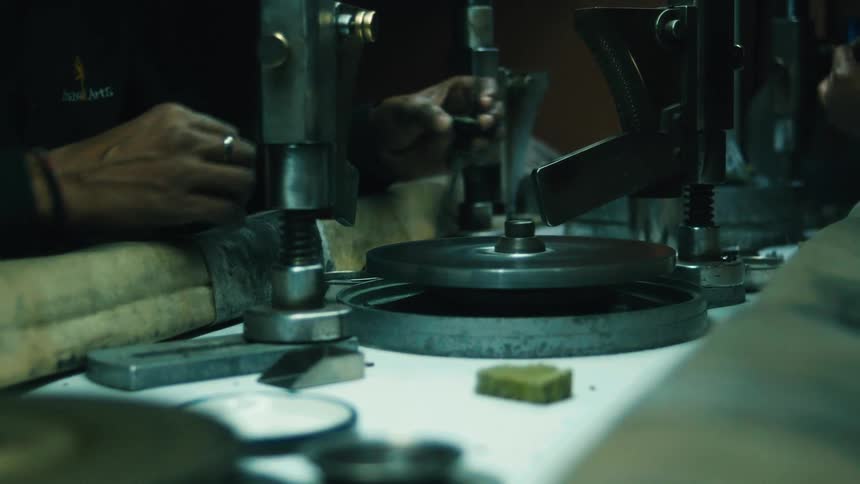 A persons hand working on a rotating machine inside a workshop at midday