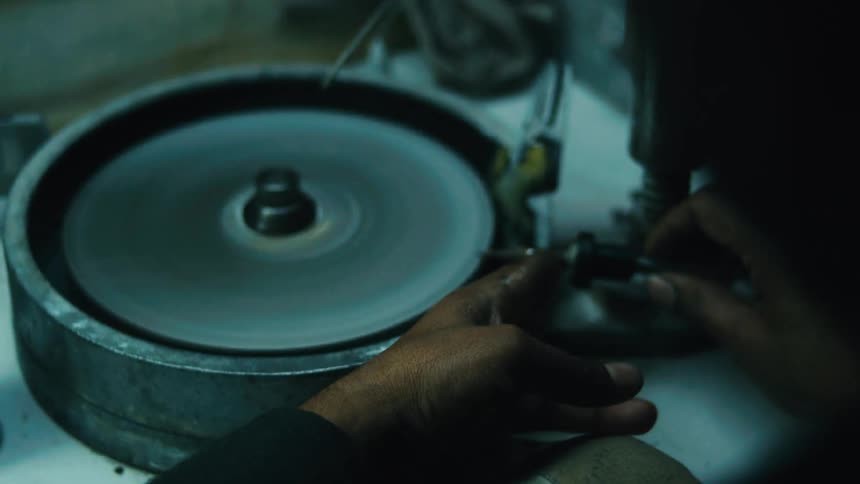 Person working on gemstone cutting with a faceting machine