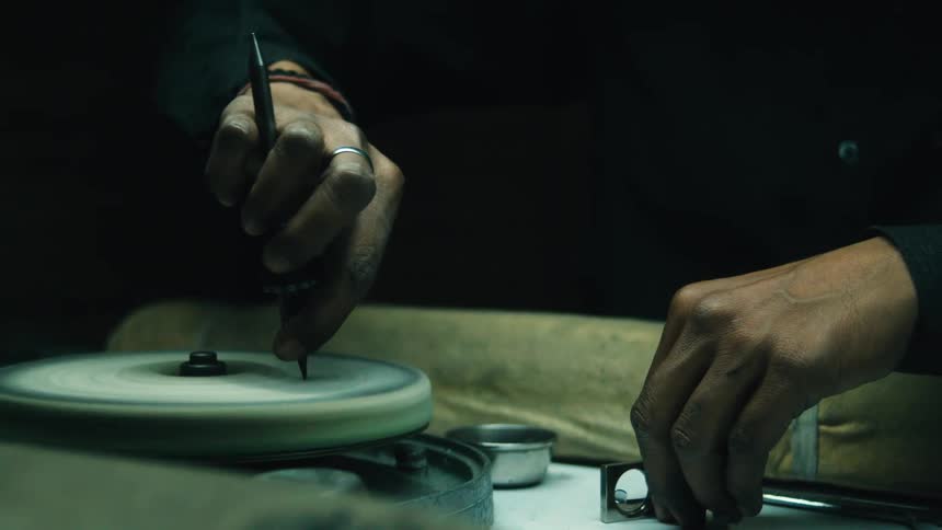 Male hands cutting a gemstone on a polishing wheel