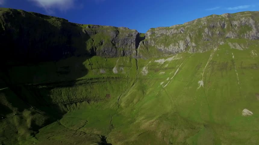 A zooming out view of some green on the side of a mountain