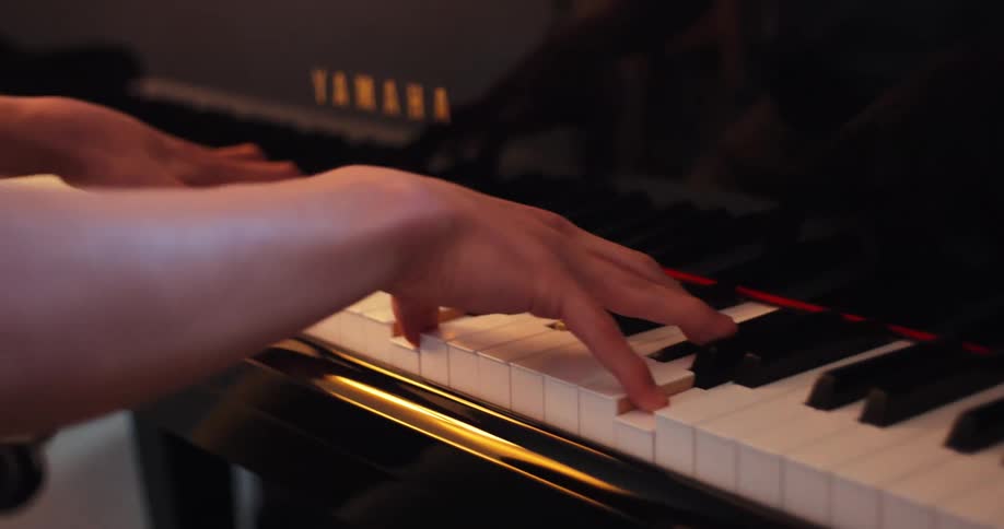 A pianists hands move gracefully across the black and white keys of a yamaha piano the pianist is playing a complex piece with their fingers flying across the keyboard in a blur of motion