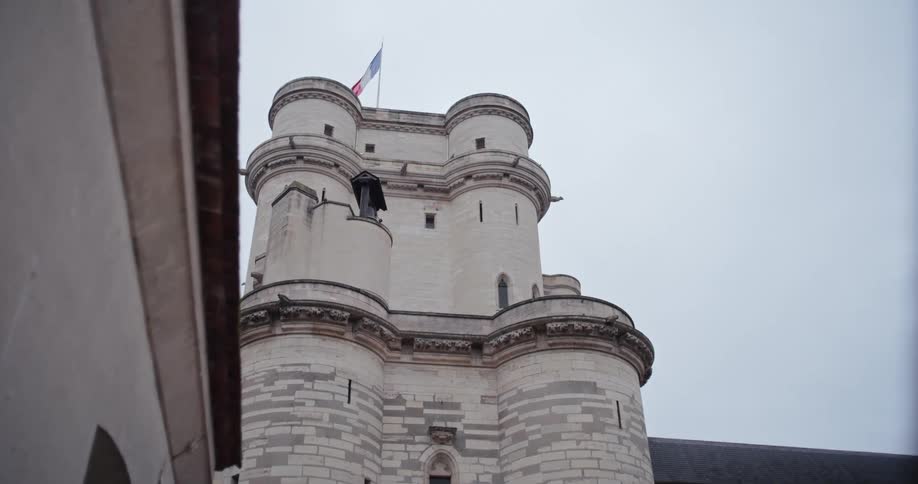 French flag on top of a castle against a cloudy sky