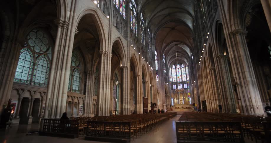 The interior of the basilica cathedral of saintdenis features intricate artistic designs and rows of benches arranged neatly