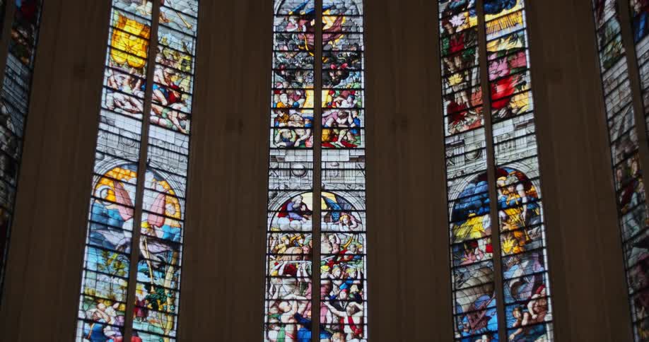 Colorful glass panels form stained glass windows in a cathedral with a high ceiling during the daytime