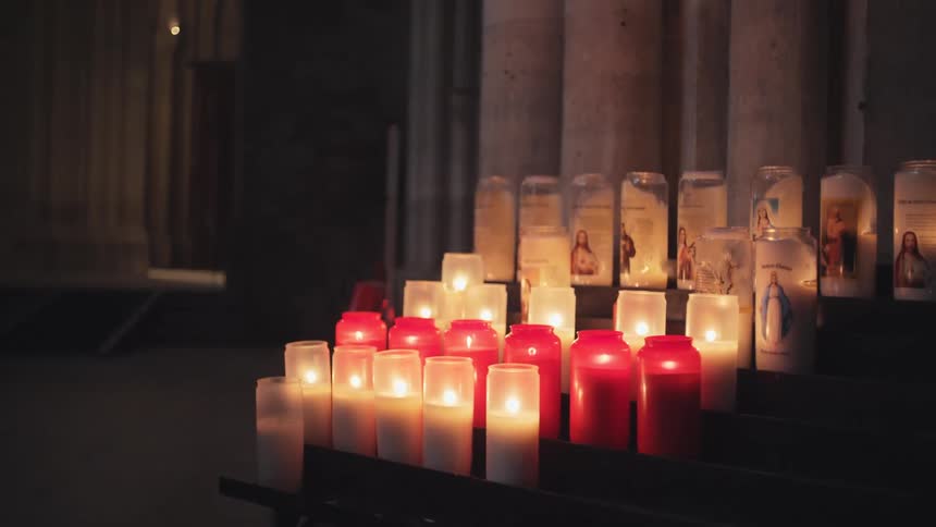 Small candles are lit as a votive offering during christian prayer in catholic churches