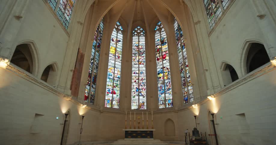 A large stained glass window at the far end of a church altar