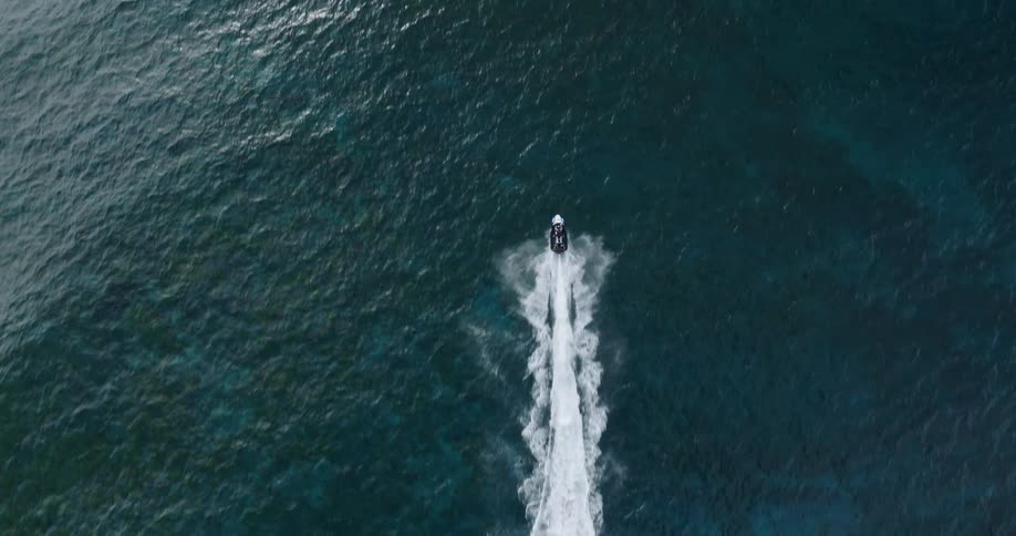 View from above of a jet ski speeding across the ocean