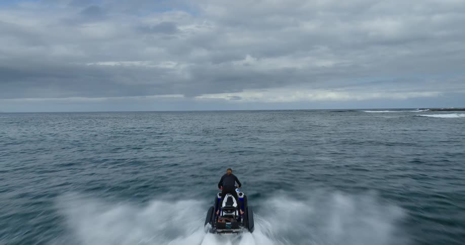 A man riding a jet ski in the ocean on a cloudy day