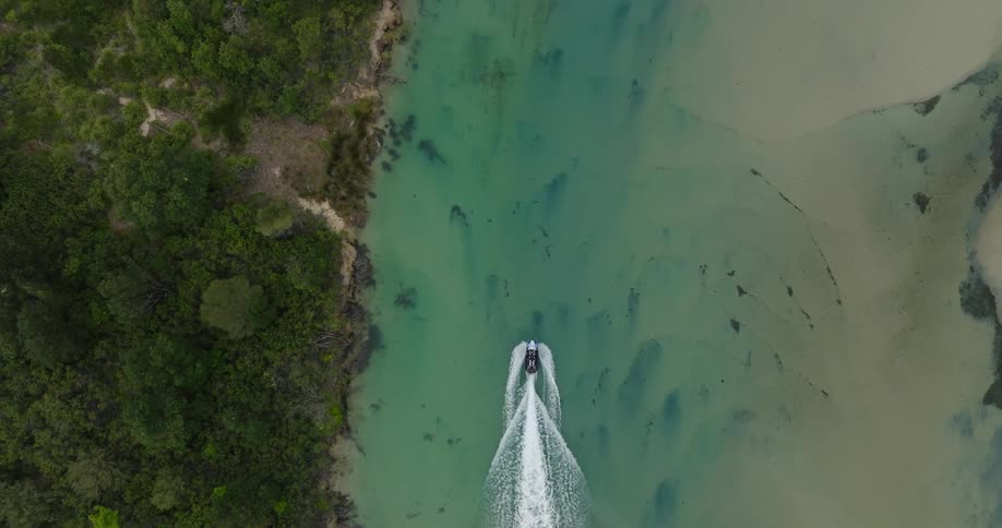Aerial view of a boat traveling through a turquoise blue sea