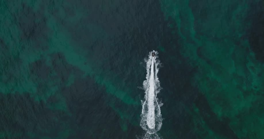 Jet ski speeding through a turquoise ocean leaving a trail in the sea