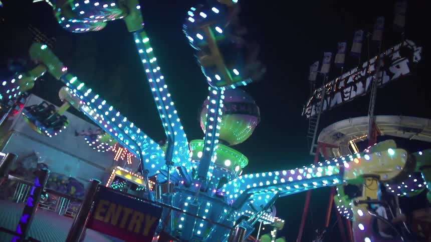 A brightly lit amusement ride carrying passengers at night time