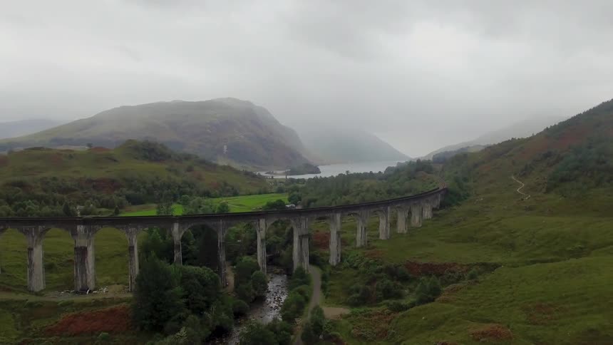 A railroad track runs on a bridge through a valley
