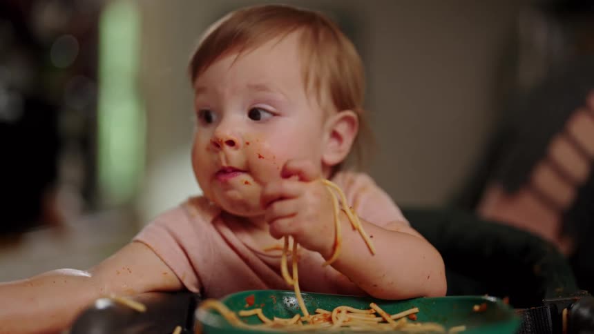 Little girl eating pasta and getting covered in sauce