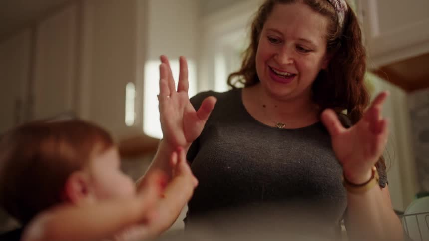 Mother waving her hands playing with her little daughter signing ASL all done