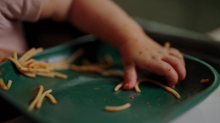 Young child sitting in a highchair eats messily