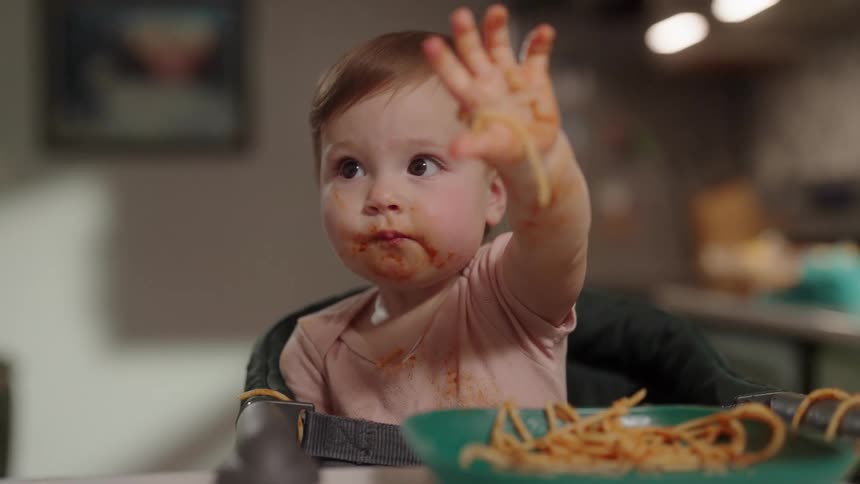 Baby playing with pasta in sauce