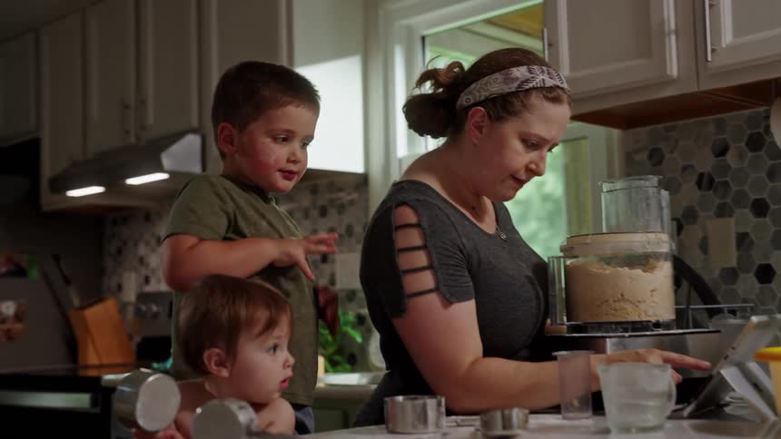 Mother with two children preparing food in the kitchen