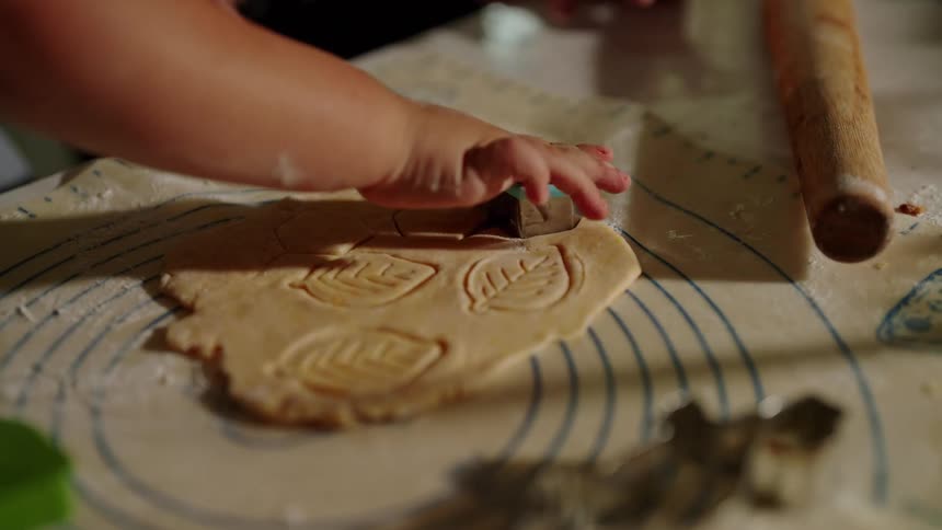 Child using a cookie cutter on rolled out dough