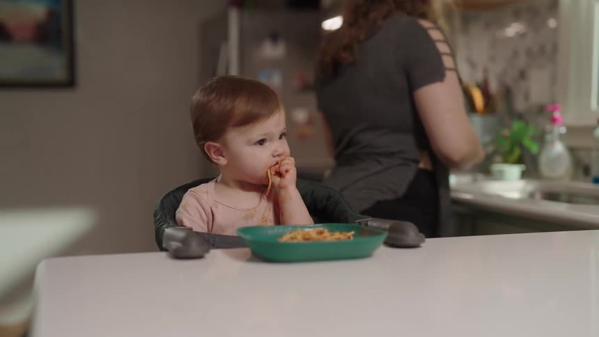 Toddler sitting at a kitchen counter eating a meal