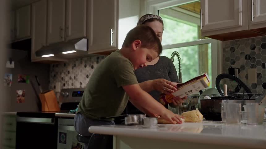 Boy helping his mother make dough in the kitchen